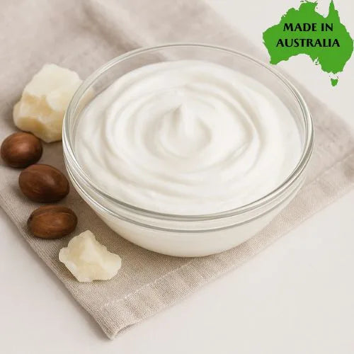 Bowl of white cream with shea butter pieces on a beige cloth, with 'Made in Australia' label.