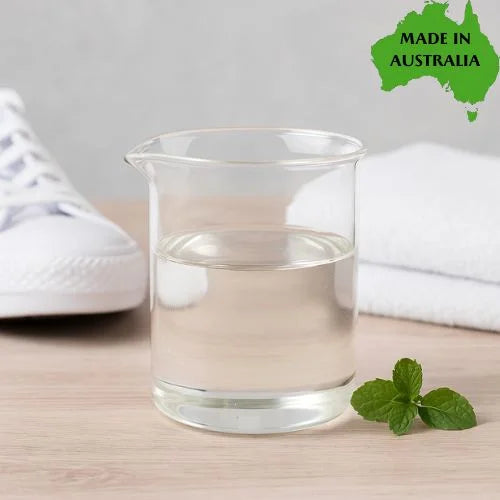 Clear glass of odour eliminator with a mint leaf and shoe on a wooden surface, with 'Made in Australia' label in the corner.
