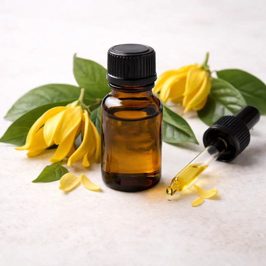 Ylang ylang complete essential oil in amber glass bottle with ylang ylang flowers in the background