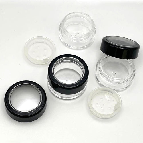 Clear 5gm pot, sifter and black rimmed lid scattered on a display area