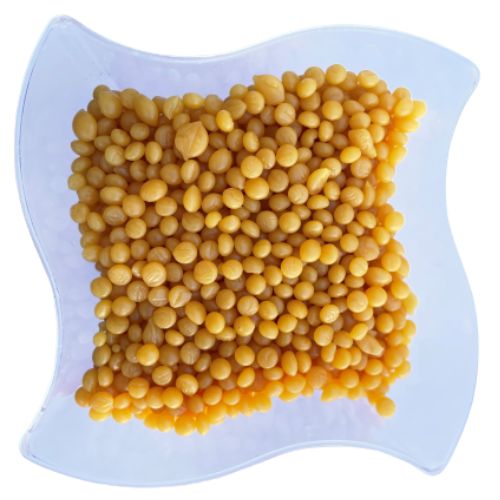 Yellow beads of candelilla wax on a white plate