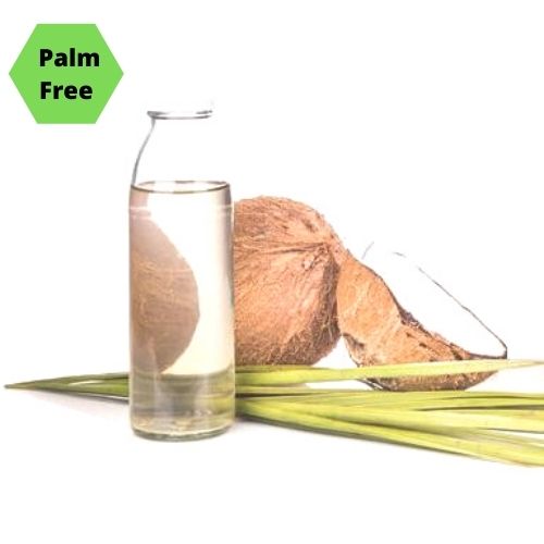 Clear fractionated coconut oil in a bottle in front of a fresh coconut