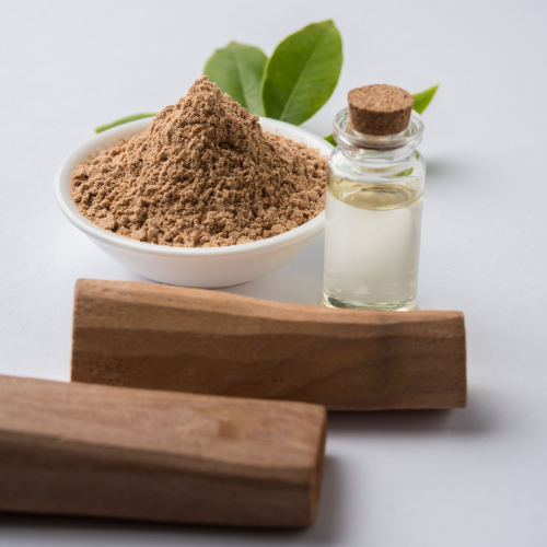 Sandalwood infused water in a bottle with a bowl of sandalwood powder and logs